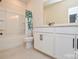 Well-lit bathroom featuring a white vanity, toilet, and shower/tub combination with a green shower curtain at 1028 Grays Mill Rd, Charlotte, NC 28215