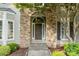 Close-up of a beautiful front door with stone archway, steps, and tasteful landscaping at 10927 Thornhill Club Dr, Charlotte, NC 28277