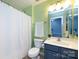 Cozy bathroom with blue vanity, white shower curtain, toilet, and green wall paint at 12328 Jessica Pl, Charlotte, NC 28269
