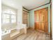 A bathroom with blue walls, modern floors, a white tub and shower combination and a wood door at 12705 Caldwell Rd, Charlotte, NC 28213