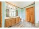 A bathroom with blue walls, modern floors, a wood double vanity, mirror and wood bi-fold closet doors at 12705 Caldwell Rd, Charlotte, NC 28213
