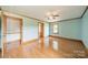 An empty bedroom with blue walls, wood trim, a ceiling fan, wood floors and two doorways at 12705 Caldwell Rd, Charlotte, NC 28213