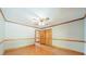 An empty bedroom with wood trim, a ceiling fan, wood floors and bi-fold doors to a closet at 12705 Caldwell Rd, Charlotte, NC 28213