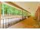 Covered porch with brick flooring and wood railing overlooking a serene wooded area at 12705 Caldwell Rd, Charlotte, NC 28213
