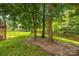 A well-manicured backyard featuring a wooden fence, lush green grass, and mature trees at 128 Sugar Thyme Ln, Mooresville, NC 28115