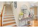 Welcoming foyer with staircase, hardwood floors, and decorative accents on a gray console table at 128 Sugar Thyme Ln, Mooresville, NC 28115