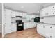 Open kitchen with white cabinets, black appliances and wood flooring, providing ample storage and workspace at 1310 Glasscock Rd, Rock Hill, SC 29730