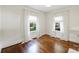 Bright bedroom features hardwood floors, fresh white walls, and natural light from two windows at 1417 The Plz, Charlotte, NC 28205