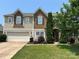 Charming two-story home with a two-car garage, stone facade accents, and a well-maintained lawn at 15105 Cavanshire Trl, Charlotte, NC 28278