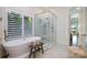 Luxurious bathroom featuring a soaking tub, walk-in shower, and plantation shutters at 17719 Springwinds Dr, Cornelius, NC 28031