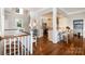 Open-concept living space featuring hardwood floors, a staircase, and a glimpse into the modern kitchen with bar seating at 17719 Springwinds Dr, Cornelius, NC 28031