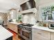 Modern kitchen featuring a professional range, custom hood, white countertops and backsplash at 2526 Sherwood Ave, Charlotte, NC 28207