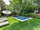 Backyard pool area featuring a rectangular pool with turf surround, lounge chairs and umbrella at 2526 Sherwood Ave, Charlotte, NC 28207