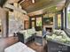 Open sunroom with brick and stone walls, tv over brick fireplace, and wood ceiling at 2526 Sherwood Ave, Charlotte, NC 28207