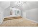 A finished bonus room with carpet flooring features stairs, a window, and a modern light fixture at 3324 Greenhurst Dr, Matthews, NC 28104