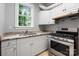 Charming kitchen with stainless steel range, light grey cabinetry, granite countertops and a bright, sunny window at 3324 Greenhurst Dr, Matthews, NC 28104