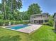 Expansive backyard with a refreshing pool, lush lawn, and the home's elegant facade at 431 Wonderwood Dr, Charlotte, NC 28211