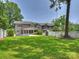Large backyard with expansive green space and the home's elegant exterior with pool view at 431 Wonderwood Dr, Charlotte, NC 28211