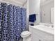 Well-lit bathroom featuring a shower with a blue patterned curtain, toilet, and a white marble vanity at 431 Wonderwood Dr, Charlotte, NC 28211