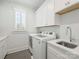 Clean laundry room with white cabinets, modern washer and dryer, and a utility sink at 431 Wonderwood Dr, Charlotte, NC 28211