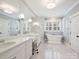 Bright main bathroom featuring double vanities, a soaking tub, and marble floors for a spa-like retreat experience at 431 Wonderwood Dr, Charlotte, NC 28211