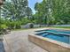 Backyard pool area featuring stone pavers, a luxurious spa, and serene landscaping at 431 Wonderwood Dr, Charlotte, NC 28211