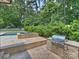 Outdoor kitchen area with a stainless steel grill, pool, spa, and travertine pavers at 431 Wonderwood Dr, Charlotte, NC 28211