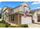 Exterior view of a brick townhome with a two-car garage, American flag, and manicured landscaping at 44409 Oriole Dr # 200, Indian Land, SC 29707
