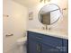 Stylish powder room with a navy vanity, marble countertop, round mirror, and elegant fixtures at 4754 Hedgemore Dr # E, Charlotte, NC 28209
