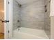 Beautifully tiled bathtub and shower featuring gray subway tiles and bronze fixtures at 4754 Hedgemore Dr # E, Charlotte, NC 28209