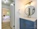 Charming bathroom featuring a blue vanity with marble countertops and a round mirror at 4754 Hedgemore Dr # E, Charlotte, NC 28209