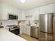 Well-lit kitchen featuring updated stainless appliances, white cabinets, and quartz countertops at 4754 Hedgemore Dr # E, Charlotte, NC 28209