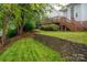 Beautiful backyard featuring a wooden deck, stone retaining wall, lush lawn, and mature shade trees at 506 Academy St, Mcadenville, NC 28101