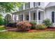 Charming front porch with a decorative wreath, black shutters, and lush landscaping at 506 Academy St, Mcadenville, NC 28101