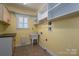 Practical laundry room with a utility sink, storage cabinets, and open shelving at 506 Academy St, Mcadenville, NC 28101