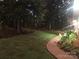 Lush backyard with mature trees, green lawn, and a paved pathway; nighttime at 524 Heritage Vw, Indian Trail, NC 28079