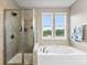 Bright bathroom featuring tiled glass shower enclosure, and a soaking tub under two windows at 537 Lakeview Dr, Mcadenville, NC 28101
