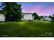 Large open backyard with lush green grass and a shed on the side of the house at twilight at 6516 Laurel Springs Ct, Charlotte, NC 28227