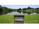Scenic view of a tranquil pond surrounded by lush trees, captured from a bench on a grassy area at 6516 Laurel Springs Ct, Charlotte, NC 28227