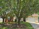 Welcoming home with attached garage, showcasing a well-maintained lawn and mature trees at 6902 Vernon Wood Ln, Charlotte, NC 28262