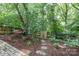 Relaxing backyard featuring a hammock, wooden fence, mature trees, and lovely greenery in a mulched area at 6935 Woodstock Dr, Charlotte, NC 28210