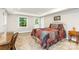Well-lit bedroom with neutral carpet, two windows, and quilt-covered bed, with additional desk and end table at 6935 Woodstock Dr, Charlotte, NC 28210