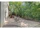 View of a spacious stone patio surrounded by mature trees and greenery, offering a private outdoor living space at 6935 Woodstock Dr, Charlotte, NC 28210