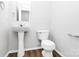 Clean half bath featuring a pedestal sink, modern toilet and laminate flooring at 7214 Fox Point Dr, Charlotte, NC 28269