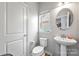 Compact half bathroom featuring pedestal sink, toilet and window at 7263 Waterwheel Sw St, Concord, NC 28025