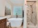 Bright bathroom featuring a soaking tub, a separate glass shower, and a stylish vanity with a window at 7810 Leisure Ln, Huntersville, NC 28078