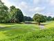Scenic view of the golf course with a pond, mature trees, and clear sky at 8026 Greenview Terrace Ct, Charlotte, NC 28277