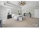 A beautiful main bedroom featuring tray ceilings, a ceiling fan, and an elegant console table at 8304 Prescott Glen Pkwy, Waxhaw, NC 28173