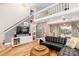 Open-concept living room with natural light, leather furniture, and a modern staircase at 10209 Green Tee Ln, Charlotte, NC 28277