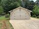 Two-car detached garage with stylish doors and concrete driveway surrounded by mature trees at 111 Kelly Ln, Gastonia, NC 28056